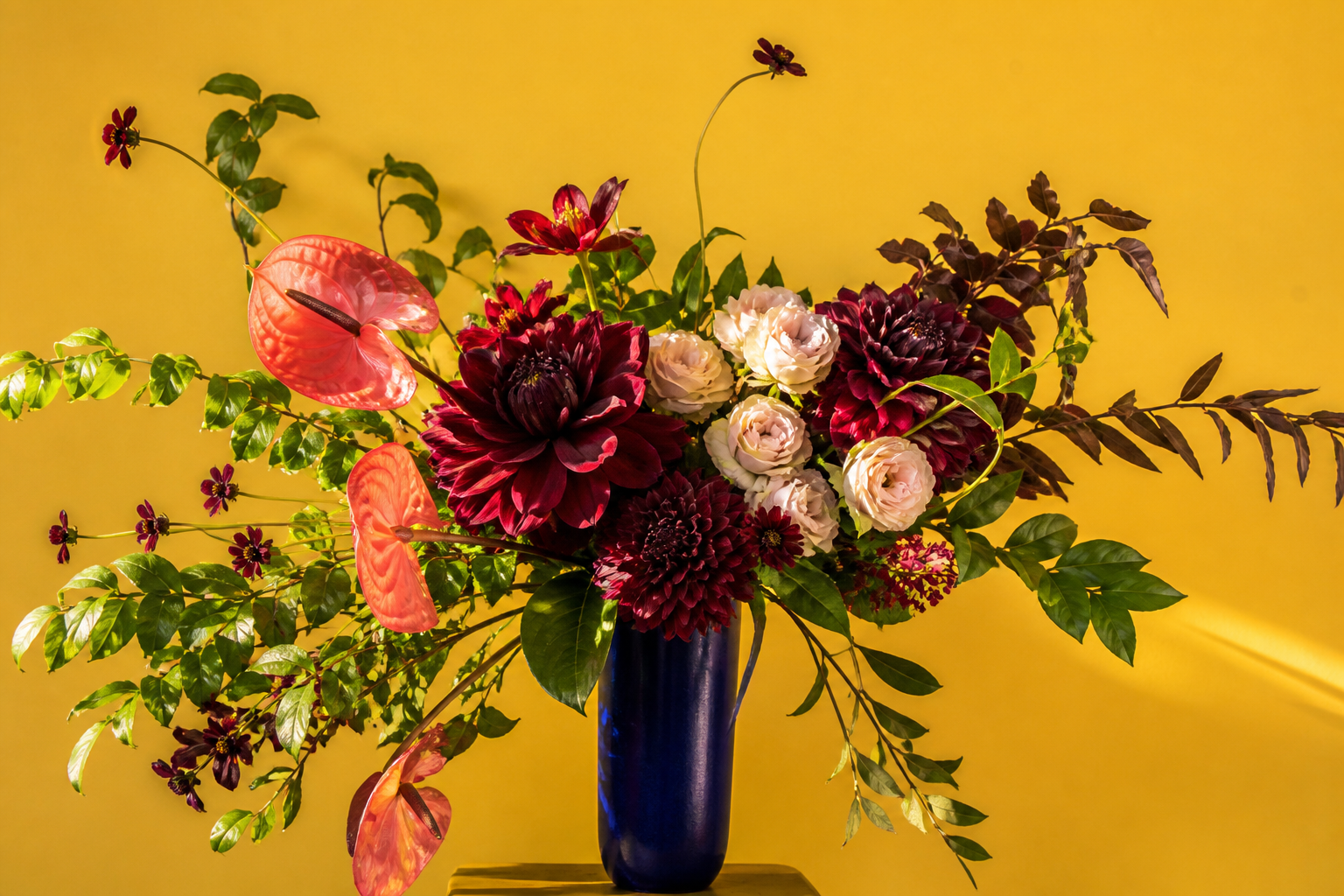 A sculptural arrangement of seasonal flowers in a stone vase