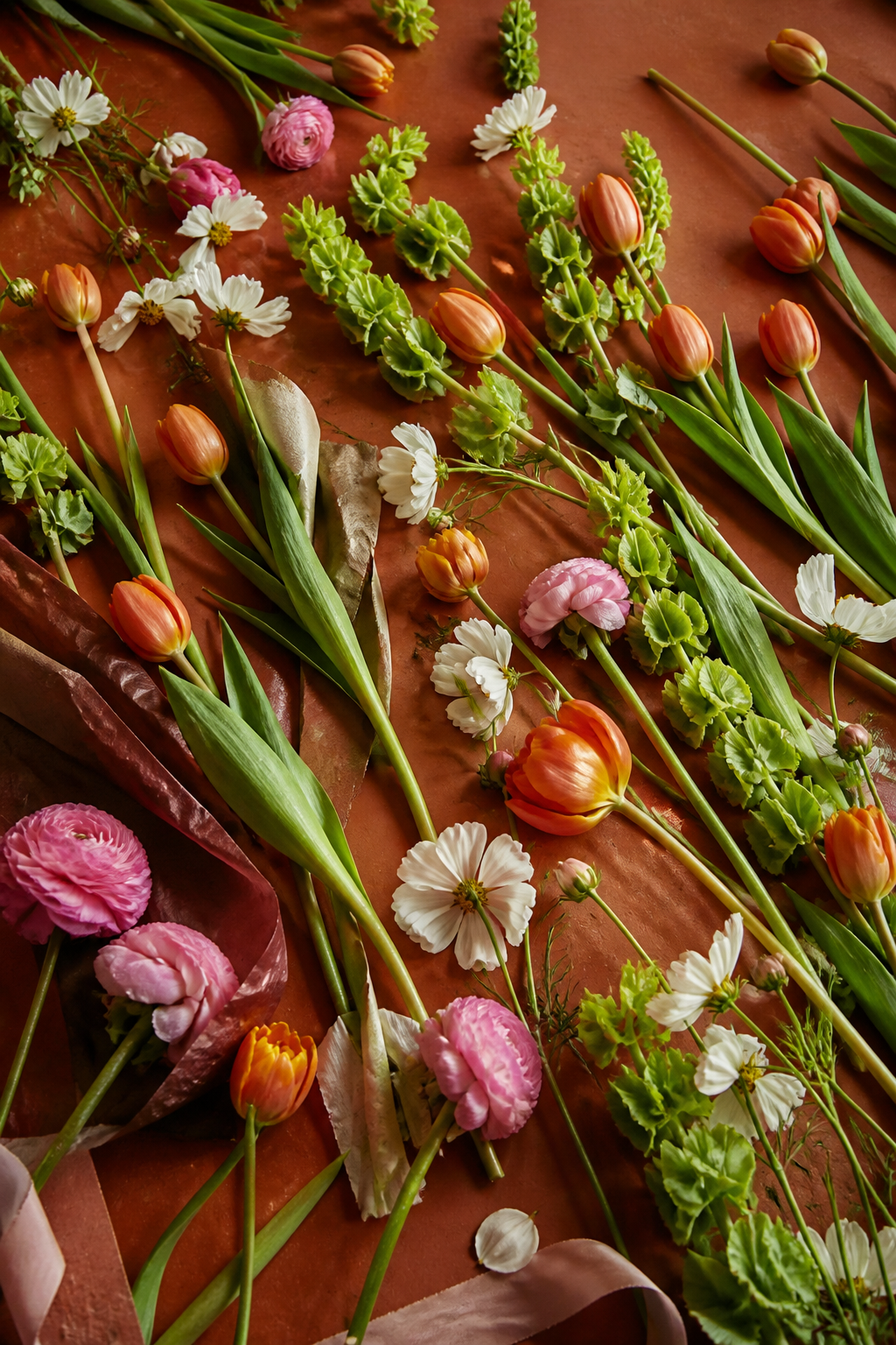 Loose seasonal flower stems arranged on a terracotta surface